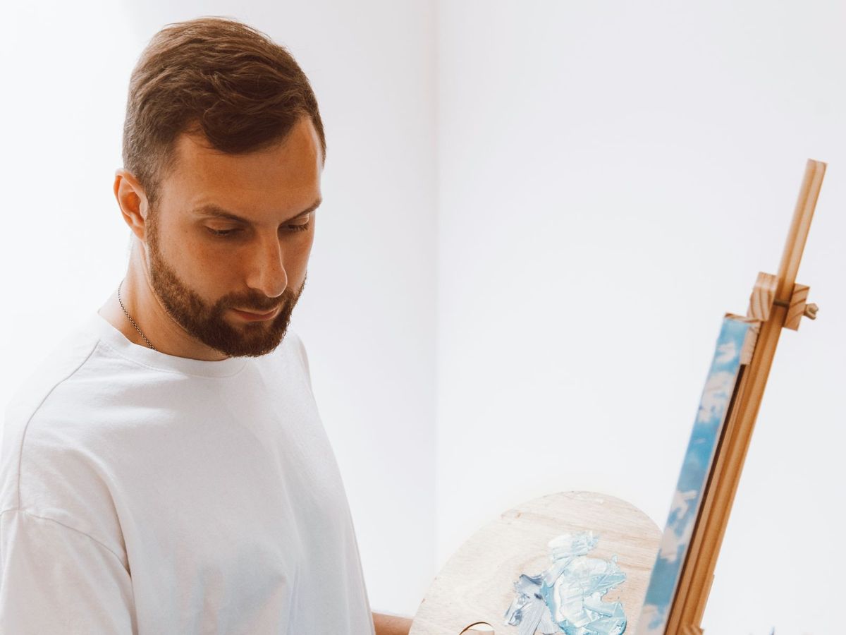 A painter holding a palette and working at an easel